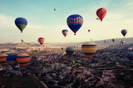 Hot air balloons rising over mountainous terrain